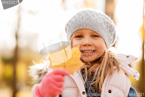 Image of happy little girl with maple leaf at autumn park