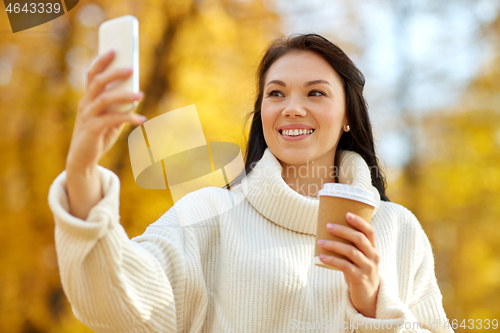 Image of woman taking selfie by smartphone at autumn park