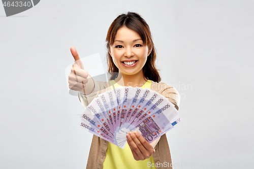 Image of asian woman with euro money showing thumbs