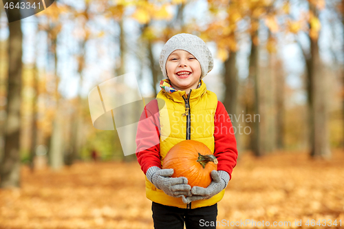 Image of happy little boy with pumpkin at autumn park