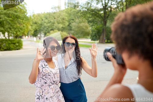 Image of woman photographing her friends in summer park