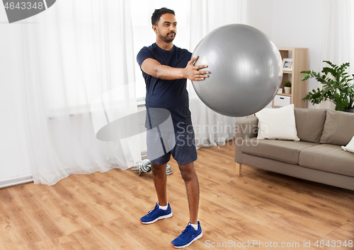 Image of indian man exercising with fitness ball at home