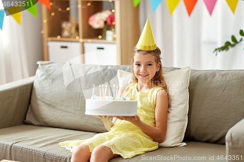 Image of nice girl in party hat with birthday cake at home