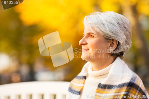 Image of portrait of happy senior woman at autumn park