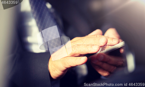 Image of senior businessman texting on smartphone in car