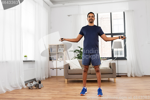 Image of indian man exercising with jump rope at home