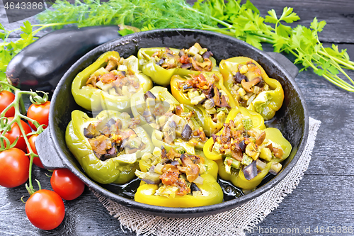 Image of Pepper stuffed with vegetables in pan on black board