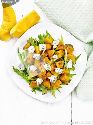 Image of Salad of pumpkin and cheese in plate on light board top