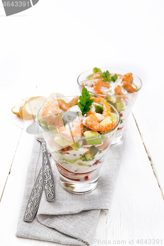 Image of Salad with shrimp and avocado in two glasses on wooden board