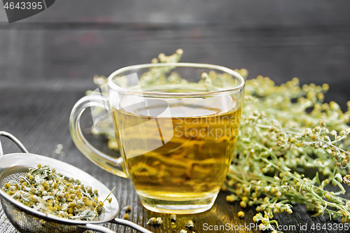 Image of Tea of gray wormwood in glass cup with strainer on board