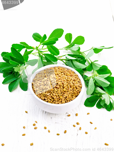 Image of Fenugreek with green leaves in bowl on white wooden board