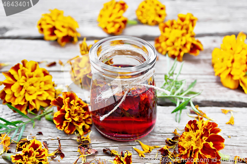 Image of Alcohol tincture of marigolds in jar on wooden board