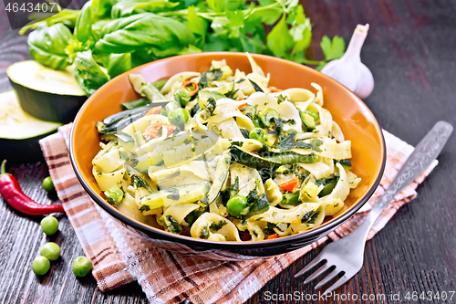 Image of Tagliatelle with green vegetables on dark wooden board