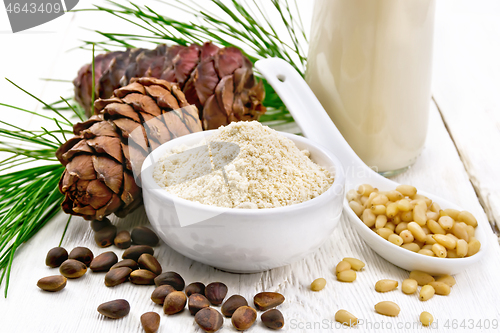 Image of Flour cedar in bowl and nuts in spoon on wooden board