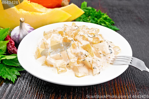 Image of Pumpkin with sour cream sauce in plate on dark wooden board