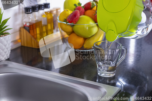 Image of Pouring filtered water into glass from jug in the kitchen