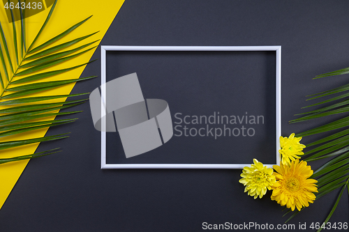 Image of Frame of tropical palm leaves with flowers on black and yellow b