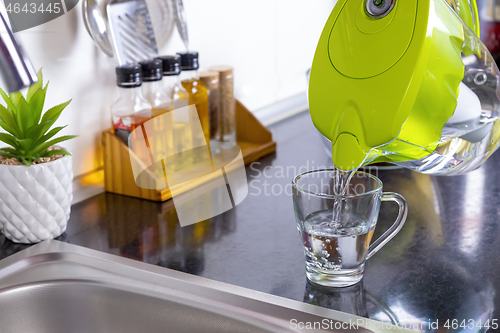 Image of Pouring filtered water into glass from jug in the kitchen