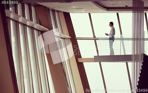 Image of young successful business man in penthouse apartment working on 