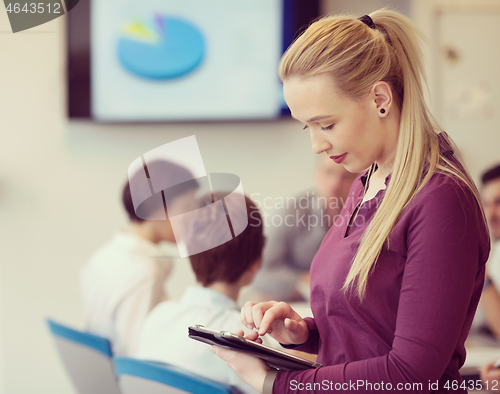 Image of blonde businesswoman working on tablet at office