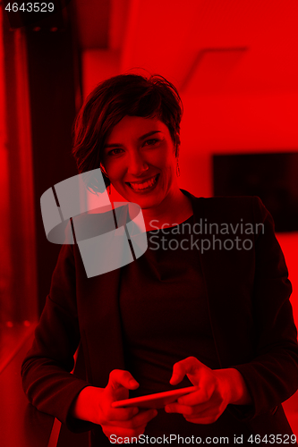 Image of Elegant Woman Using Mobile Phone by window in office building