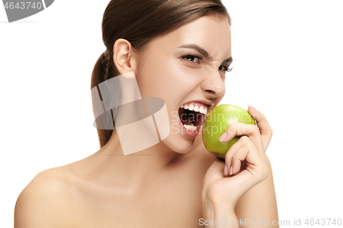 Image of portrait of attractive caucasian smiling woman isolated on white studio shot eating green apple