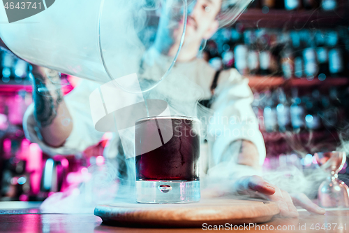 Image of Expert barman is making cocktail at night club.