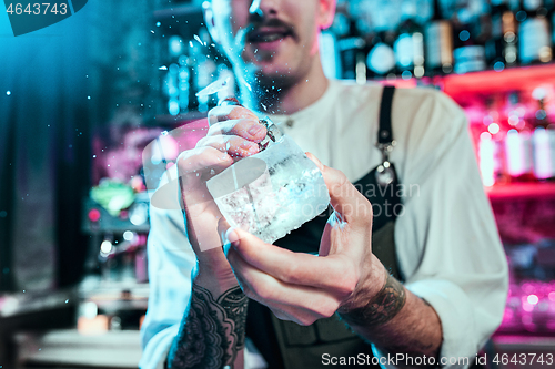 Image of Expert barman is making cocktail at night club.