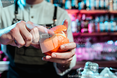 Image of Expert barman is making cocktail at night club.