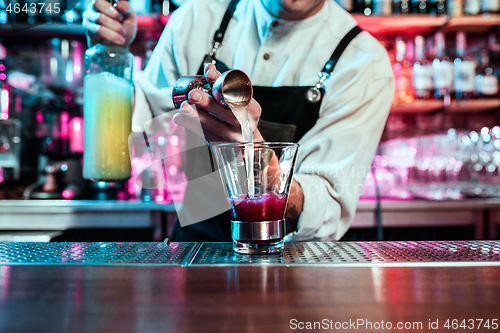 Image of Expert barman is making cocktail at night club.