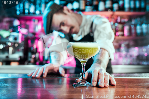 Image of Expert barman is making cocktail at night club.