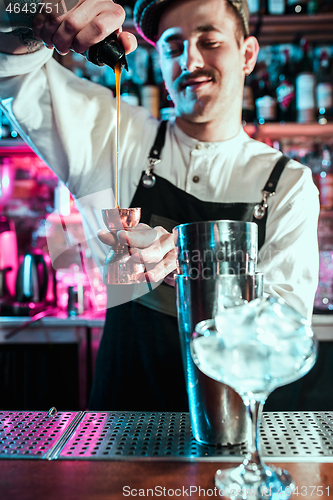 Image of Expert barman is making cocktail at night club.