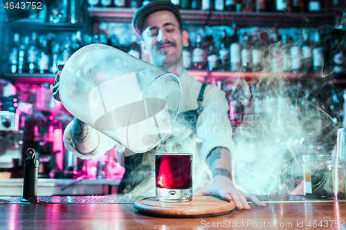 Image of Expert barman is making cocktail at night club.