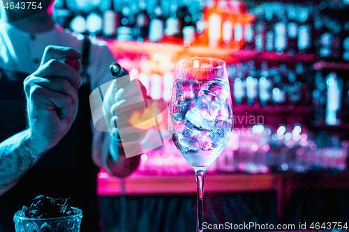 Image of Expert barman is making cocktail at night club.