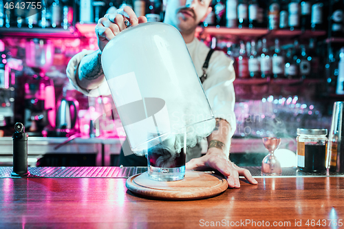 Image of Expert barman is making cocktail at night club.