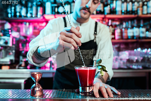 Image of Expert barman is making cocktail at night club.