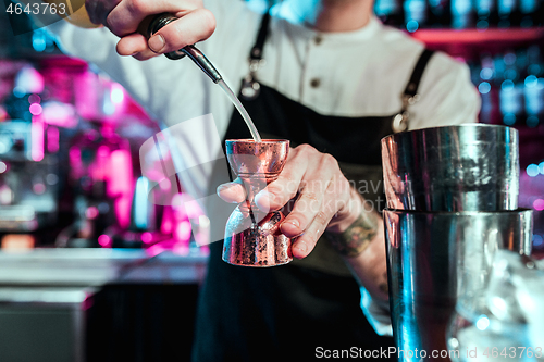 Image of Expert barman is making cocktail at night club.