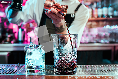 Image of Expert barman is making cocktail at night club.