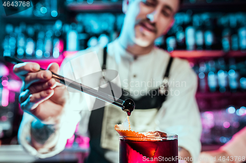 Image of Expert barman is making cocktail at night club.