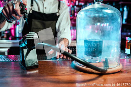 Image of Expert barman is making cocktail at night club.