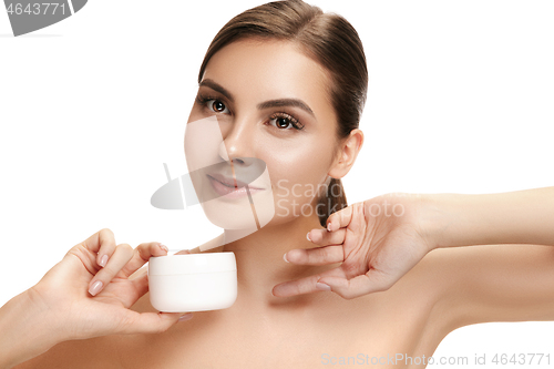 Image of Cute girl preparing to start her day. She is applying moisturizer cream on face.