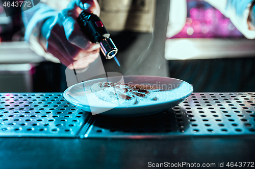 Image of Expert barman is making cocktail at night club.