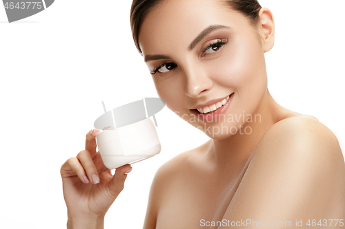 Image of Cute girl preparing to start her day. She is applying moisturizer cream on face.