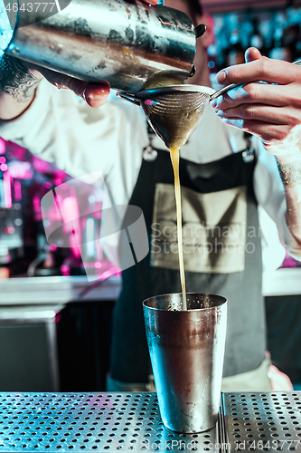 Image of Expert barman is making cocktail at night club.