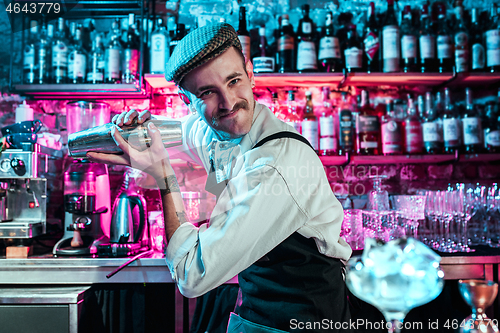 Image of Expert barman is making cocktail at night club.