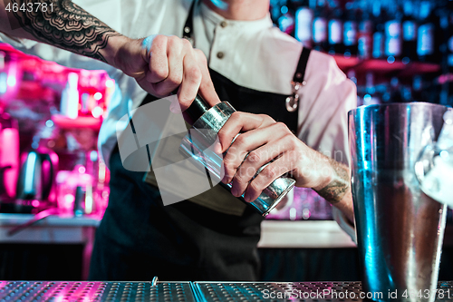 Image of Expert barman is making cocktail at night club.