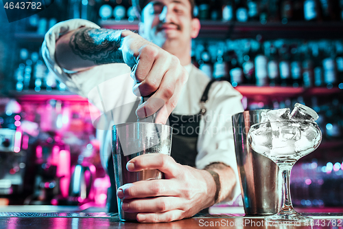 Image of Expert barman is making cocktail at night club.