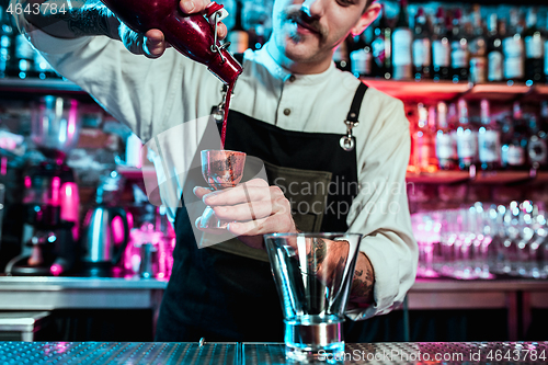 Image of Expert barman is making cocktail at night club.