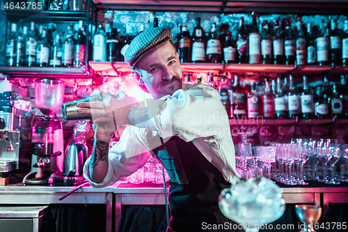 Image of Expert barman is making cocktail at night club.