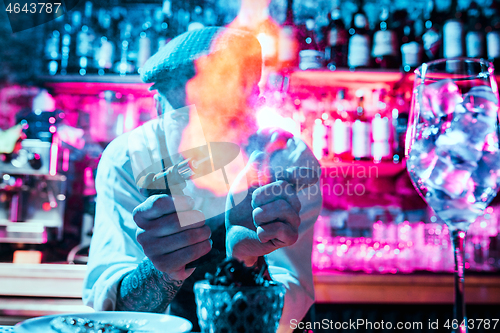 Image of Expert barman is making cocktail at night club.